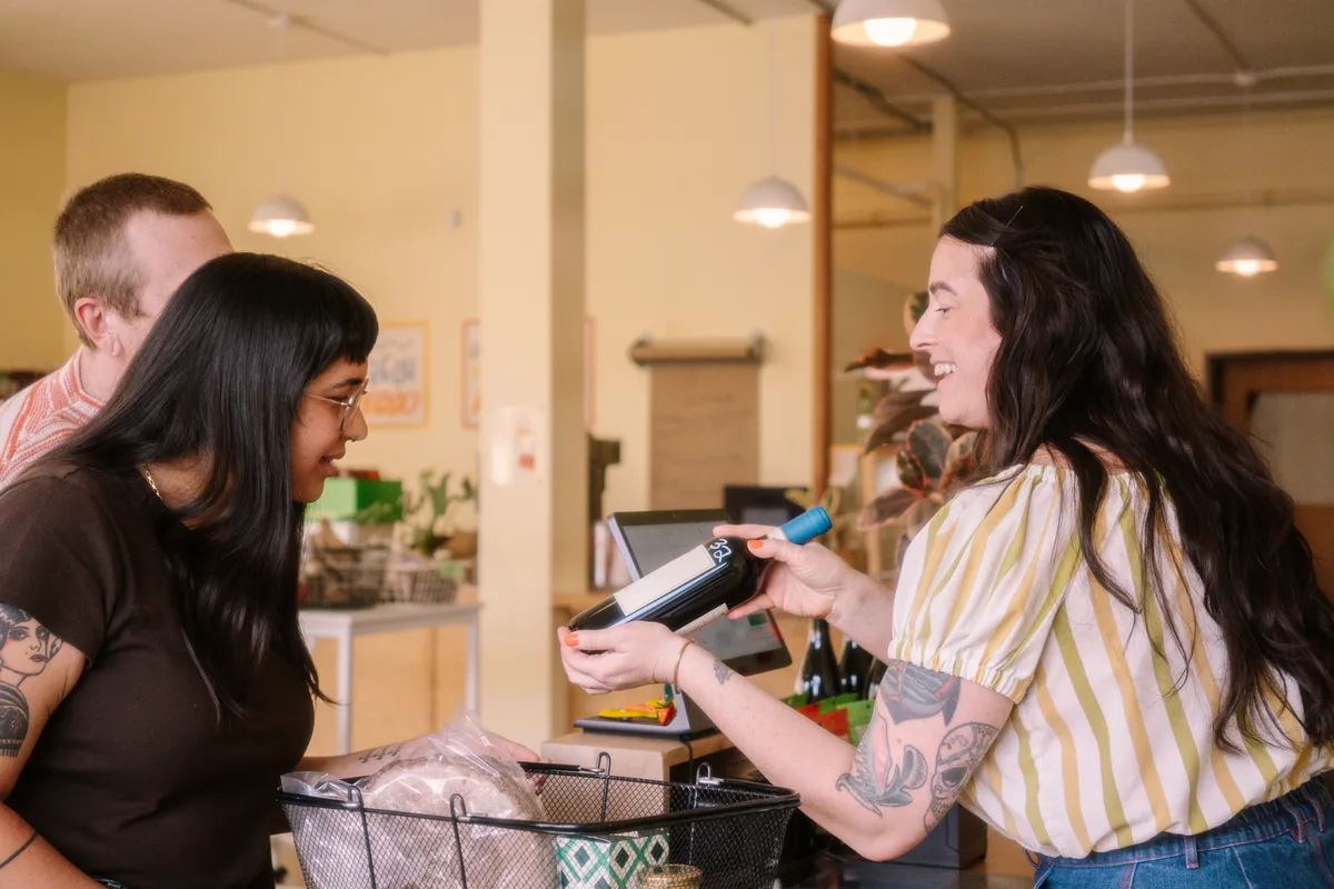 Local shop owner helping a customer at the checkout counter