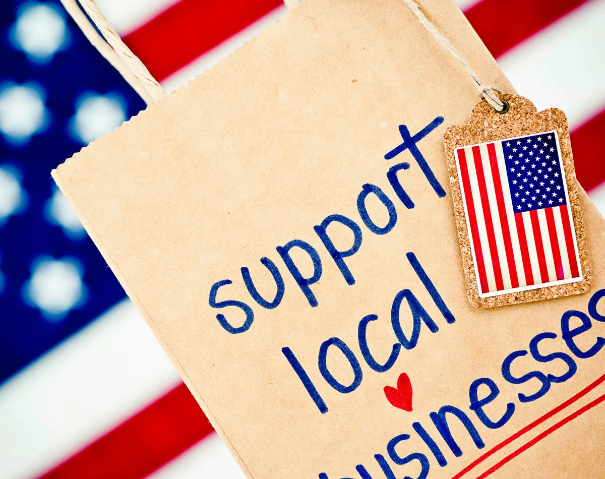 Support local businesses shopping bag in front of an American flag
