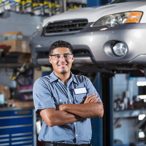 Auto mechanic standing by a car on a lift