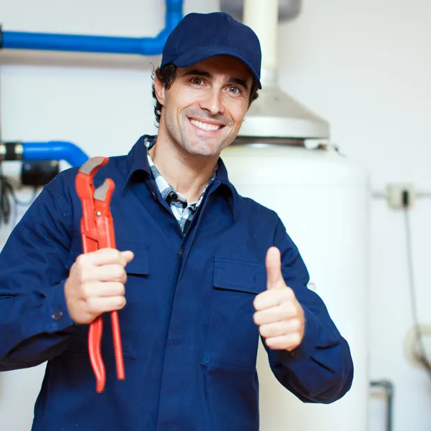 Ashburn plumber with a wrench beside a water heater