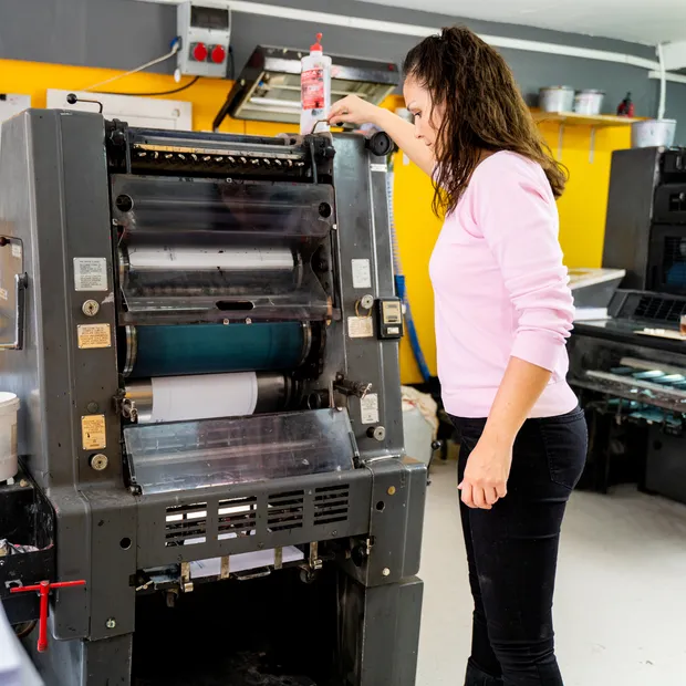 Print shop owner operating a printing press